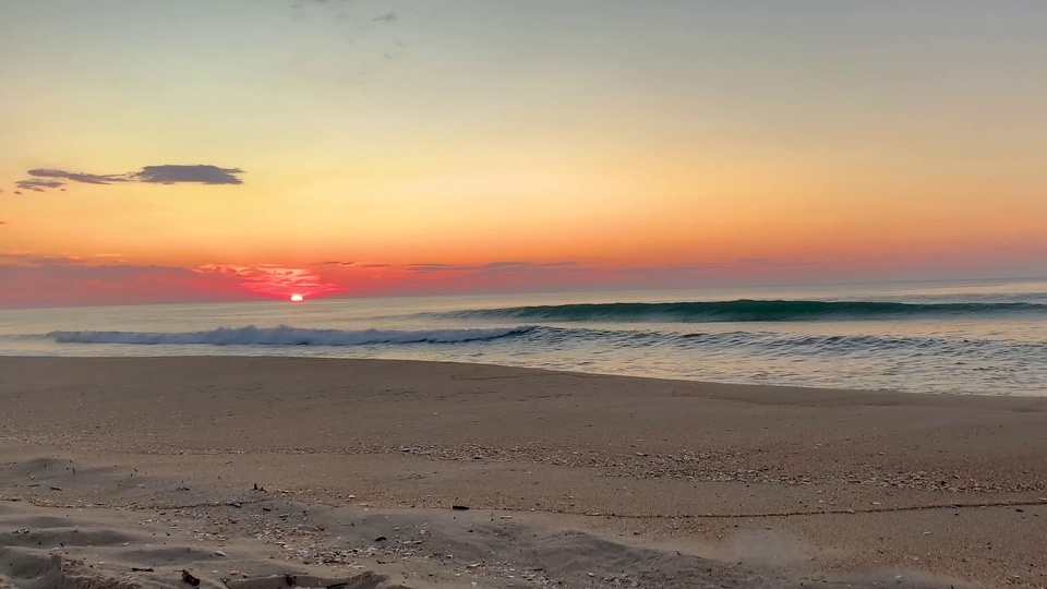 Sunset waves crashing against the beach